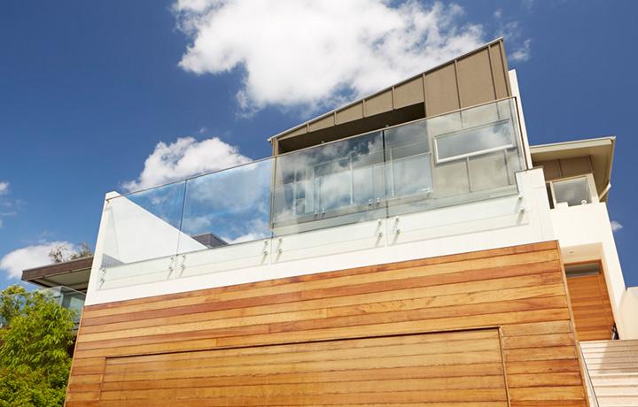 Contemporary style two story home lit by bright sunlight and blue sky with clouds in background